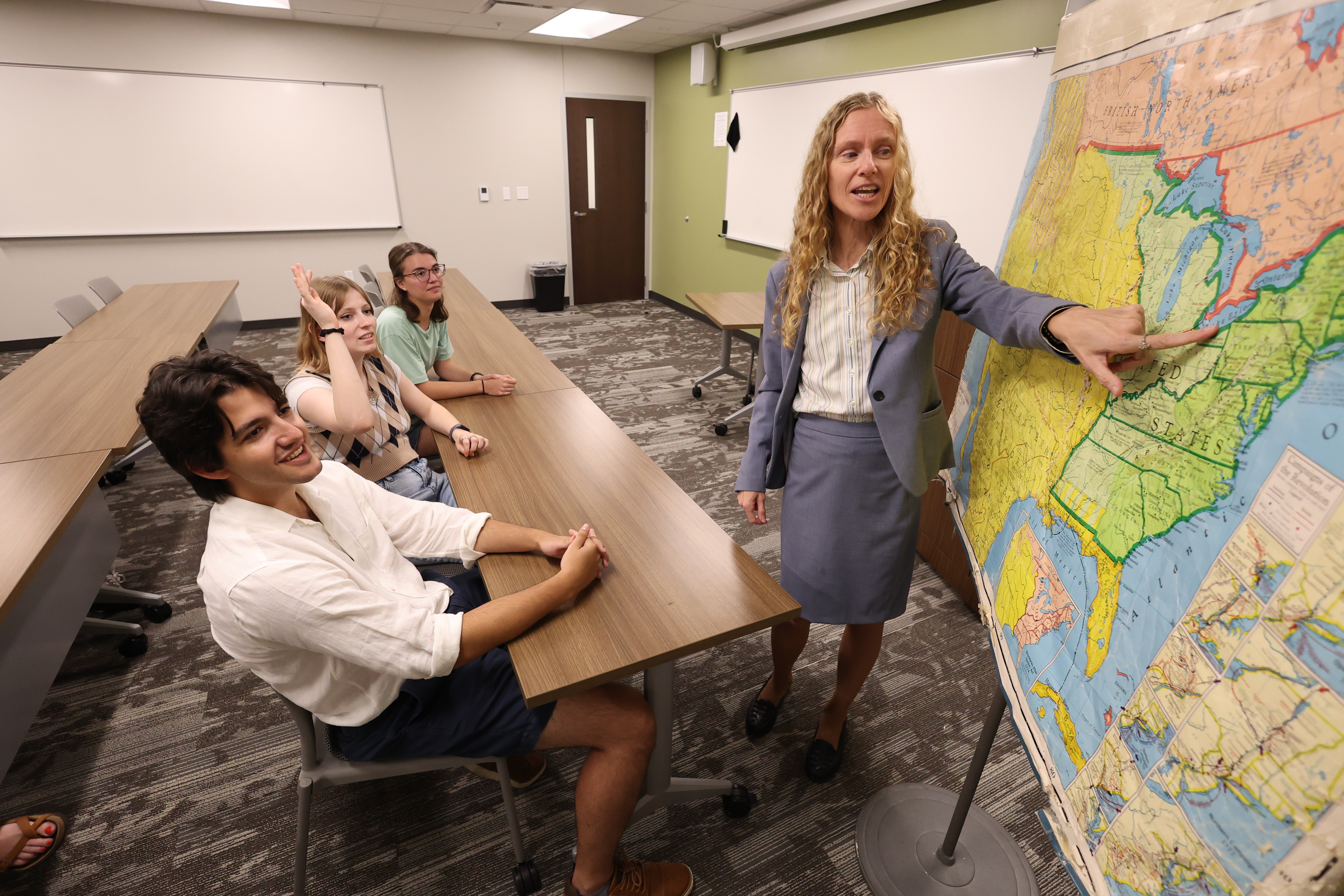 faculty pointing to map in front of three students