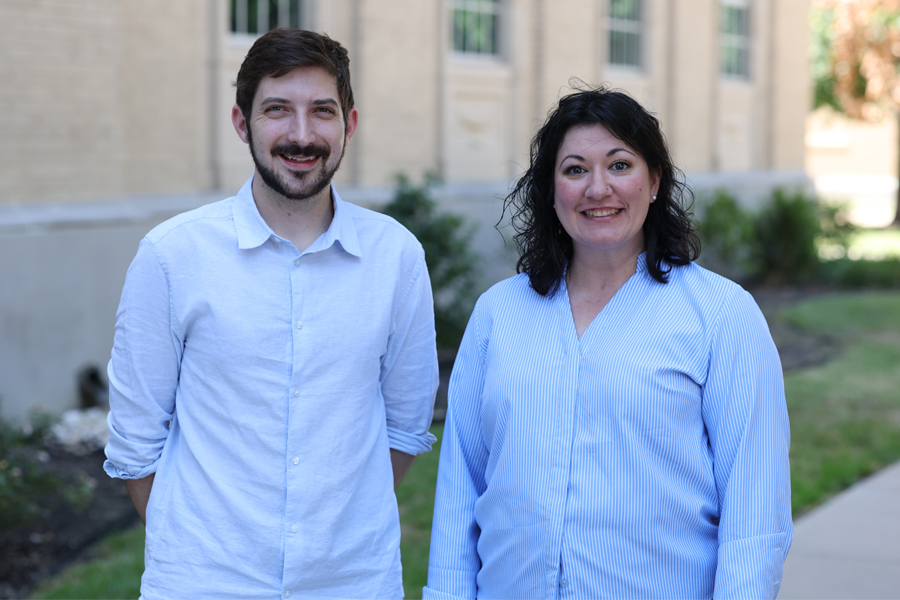 two faculty standing in front of building