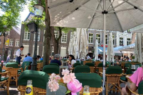 Cafe tables with umbrellas and patrons in Maastricht, Netherlands