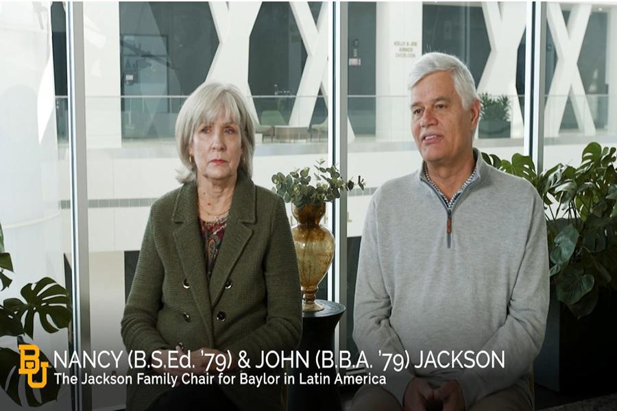 A woman and a man sit facing the camera talking