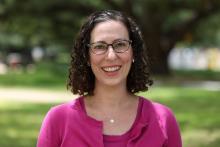 Andrea Turpin wears a pink shirt and cardigan and faces the camera smiling
