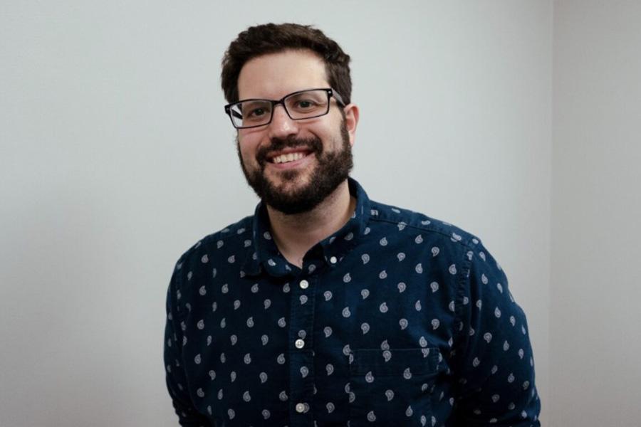 Dr. Anthony Gaspar wears a blue collared shirt and smiles at the camera