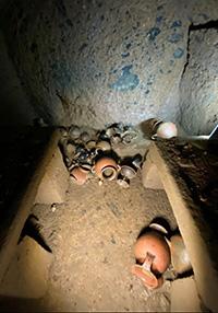 Ceramic pots litter the floor of an Etruscan tomb