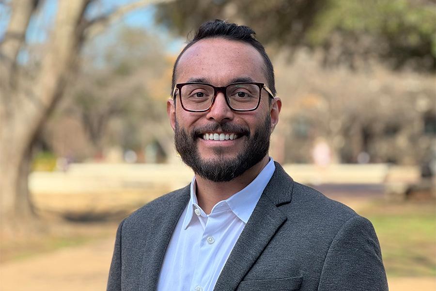 Dr. Ricardo Alvarez-Pimental wears a suit and stands outside facing the camera smiling