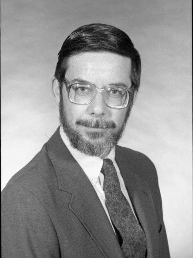 David Longfellow wears suit and smiles at the camera in black and white photograph