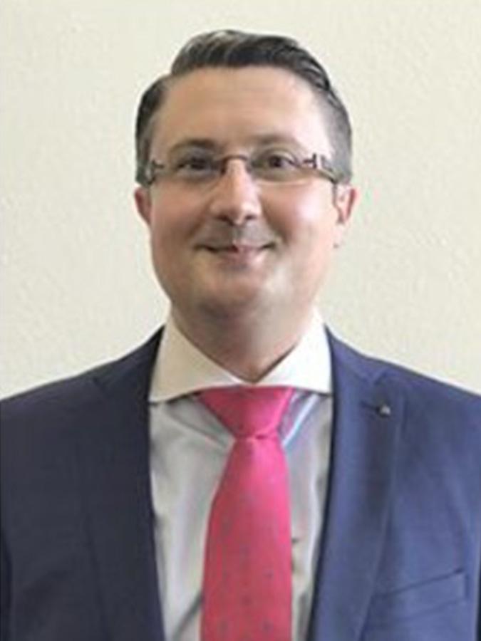 Dr. Bratu wears a suit and smiles at the camera