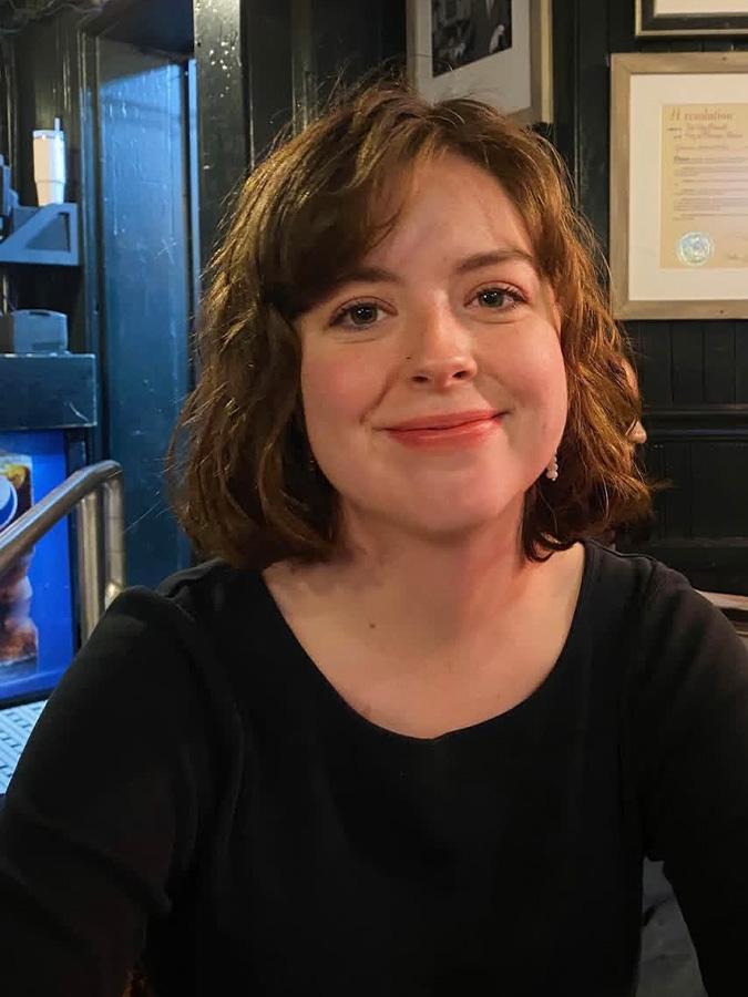 Katherine Cox wears a black shirt and smiles at the camera.