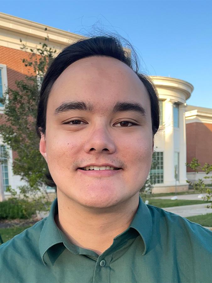 Aaron Ramos wears a green shirt and smiles at the camera.