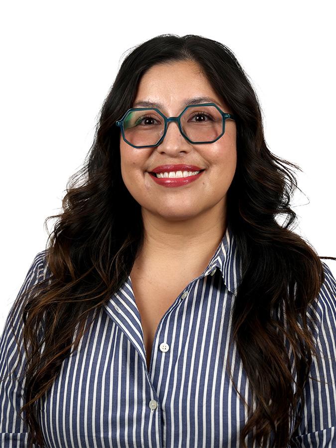 Dr. Ruth Oropeza wears a striped shirt and smiles at the camera. 